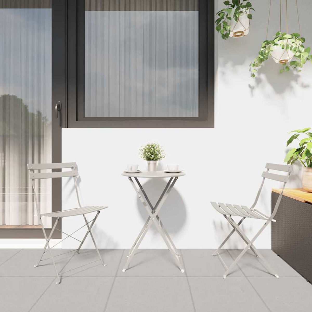 Ein kleiner runder Tisch mit zwei Stühlen auf einer gefliesten Terrasse. Auf dem Tisch steht eine kleine Pflanze. Fenster im Hintergrund.