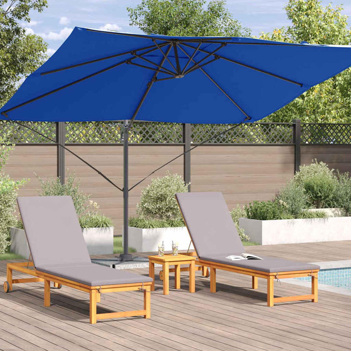Due lettini grigi sotto un ombrellone blu su una terrazza di legno. Un tavolino è tra loro. Lo sfondo mostra verde e recinzione.