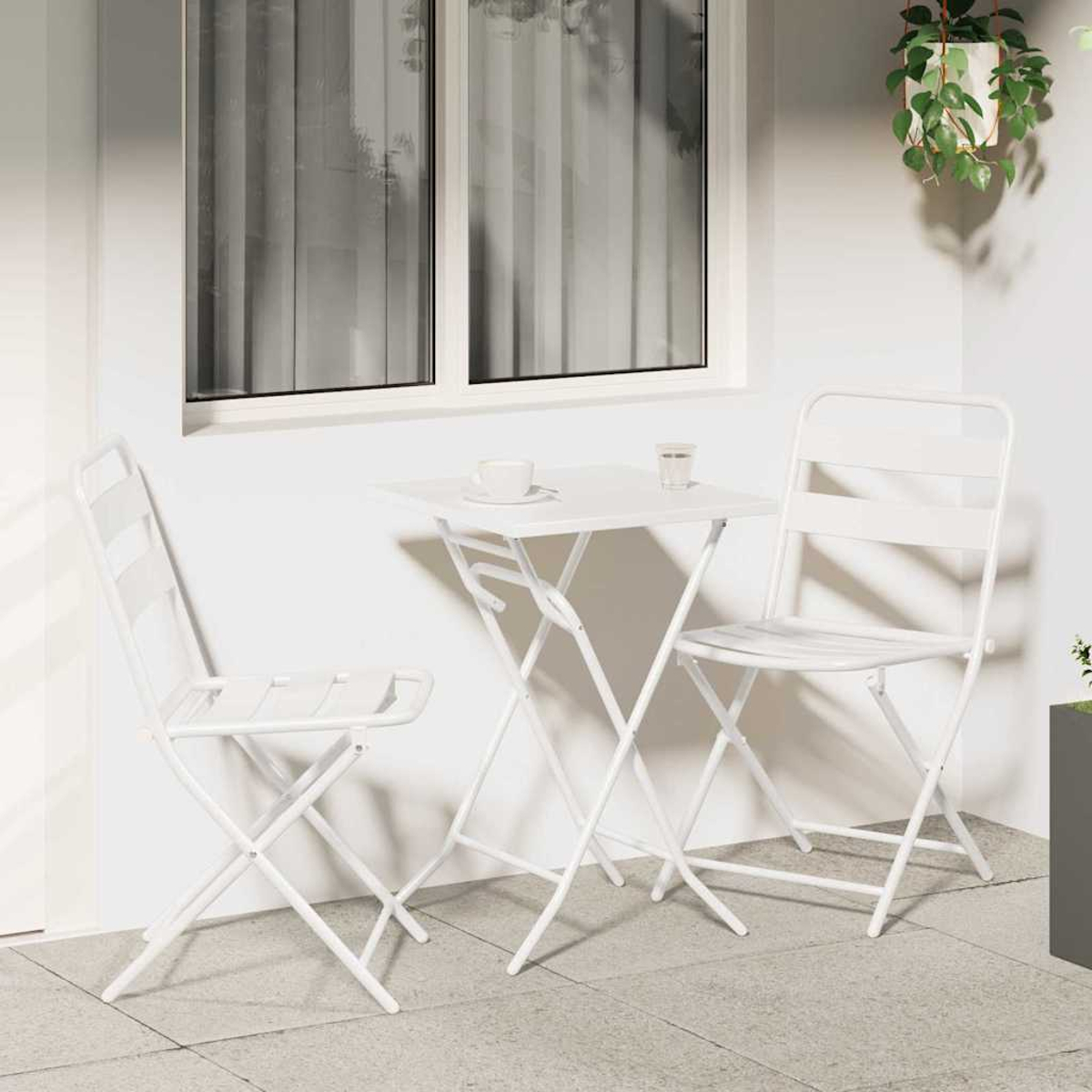 Weißes Terrassenset mit Tisch, zwei Stühlen und einer kleinen Tasse. Ein Fenster befindet sich hinter dem Set. Pflanzen sind rechts.