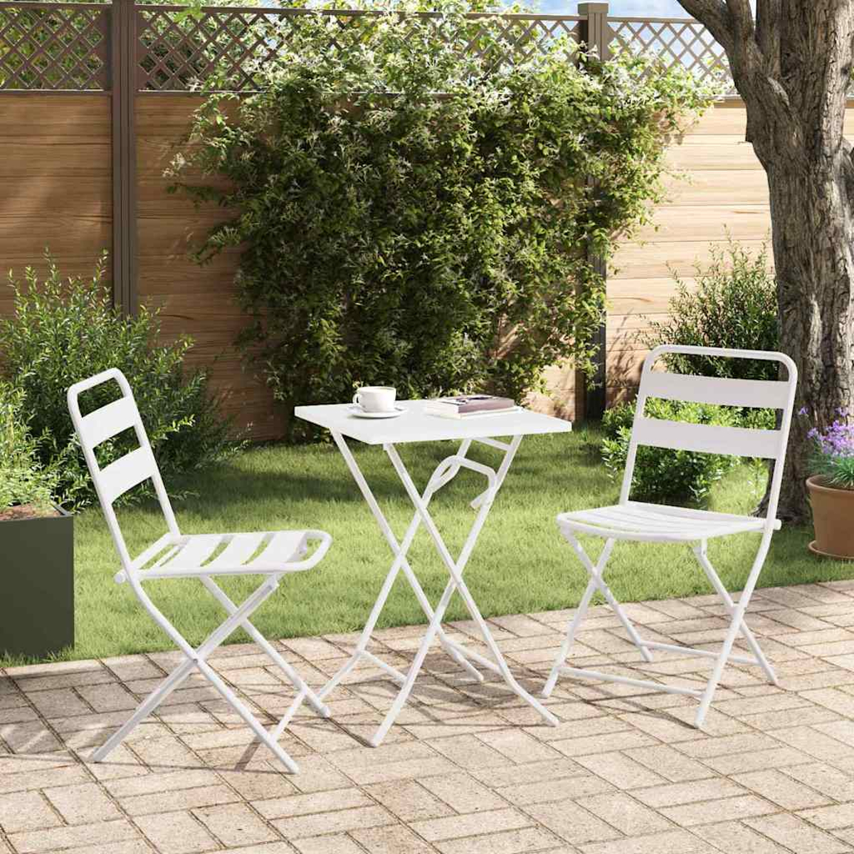 Weißer Tisch und Stühle auf der Terrasse. Eine Tasse und ein Buch liegen auf dem Tisch. Grüne Pflanzen und ein Baum im Hintergrund.