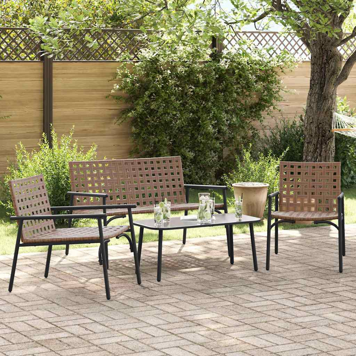 Terrassenset im Freien mit einer Bank, zwei Stühlen und einem Tisch. Getränke auf dem Tisch. Üppiges Grün und Holzzaun im Hintergrund.