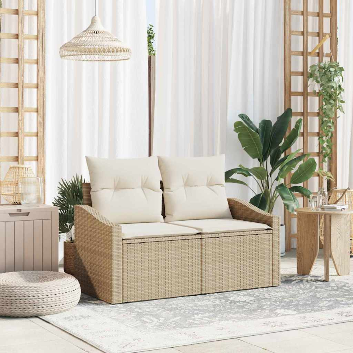 Un divano in rattan con cuscini color crema è su un tappeto. Piante e un tavolino con un bicchiere sono nelle vicinanze.