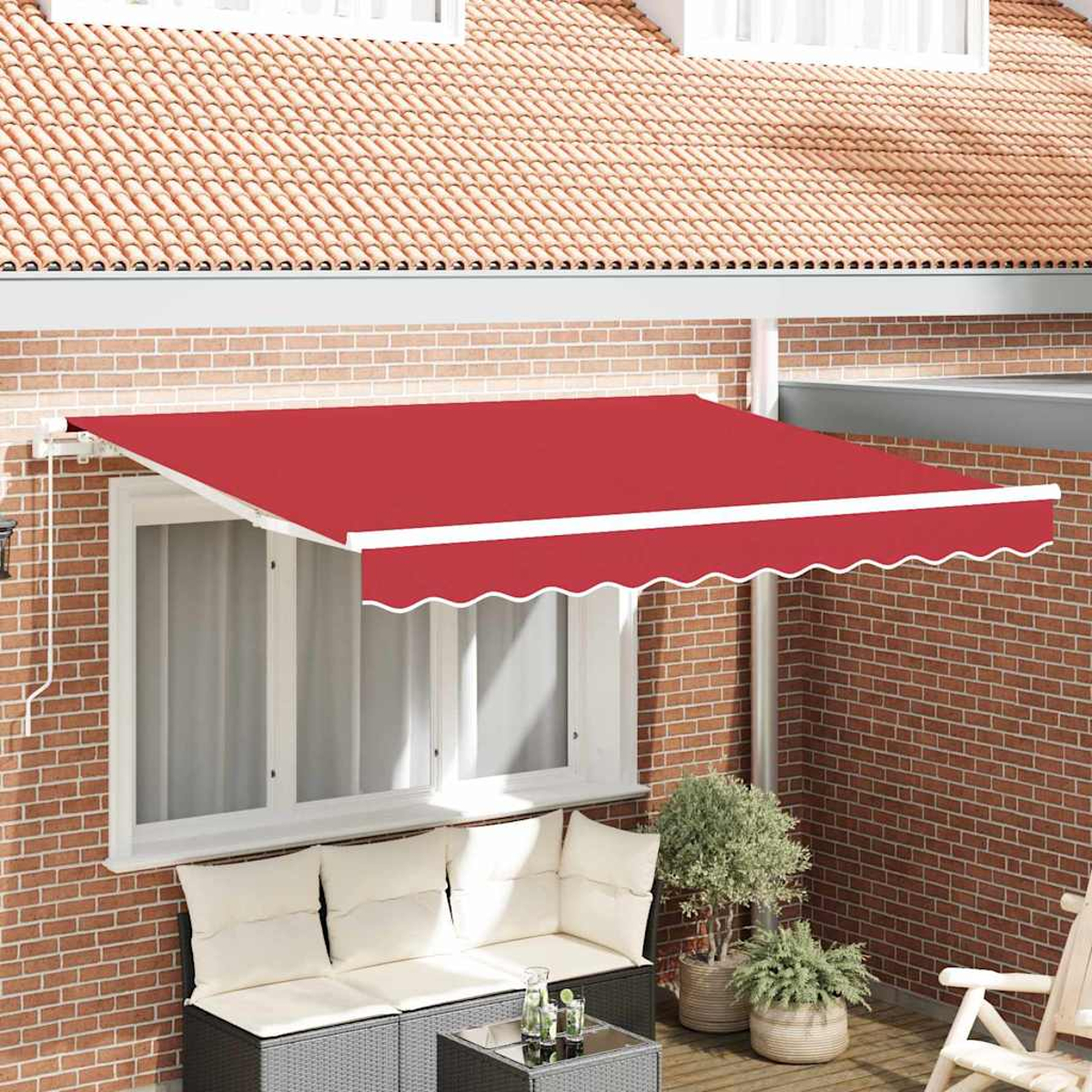 Ein rotes Sonnensegel erstreckt sich über einem Fenster und einer Terrasse. Ziegelmauer, Pflanzen und Sofa sichtbar.