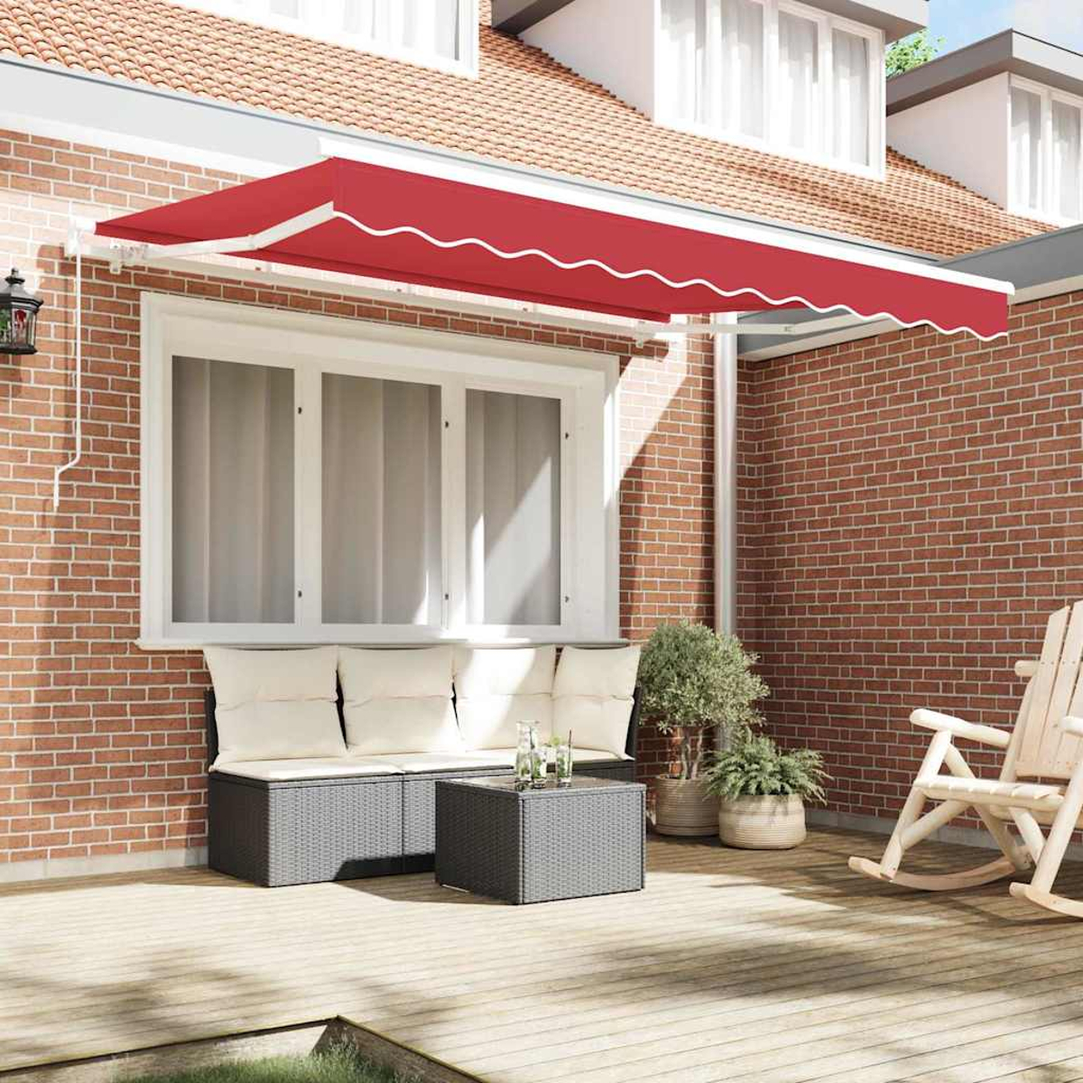 Rote Markise über einer Terrasse mit Korbmöbeln, Pflanzen und einem Schaukelstuhl. Ziegelmauer und ein Haus im Hintergrund.