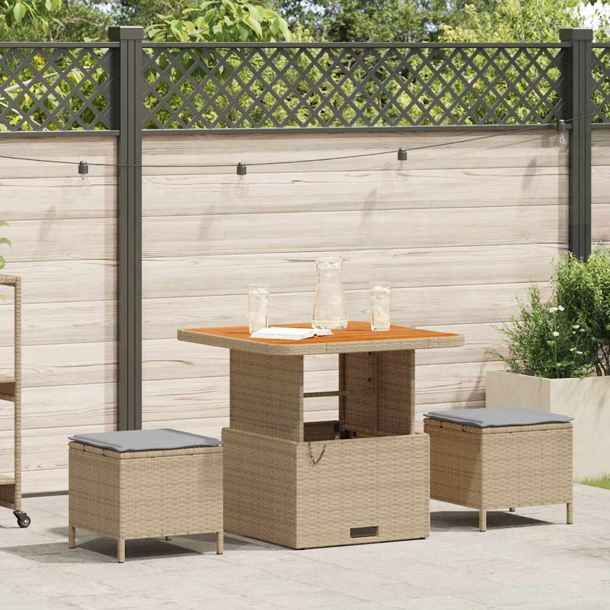 Terrassengarnitur mit Tisch, zwei Hockern und Zaun im Hintergrund. Tisch hat Holzplatte, Hocker graue Kissen.