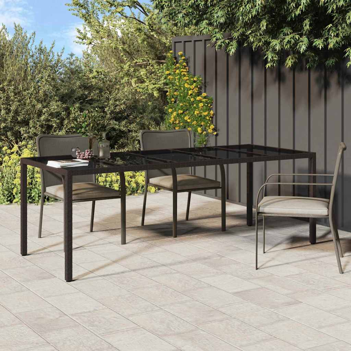 Una escena de comedor al aire libre con una mesa y sillas. Plantas verdes en el fondo. La mesa tiene una tapa de cristal.