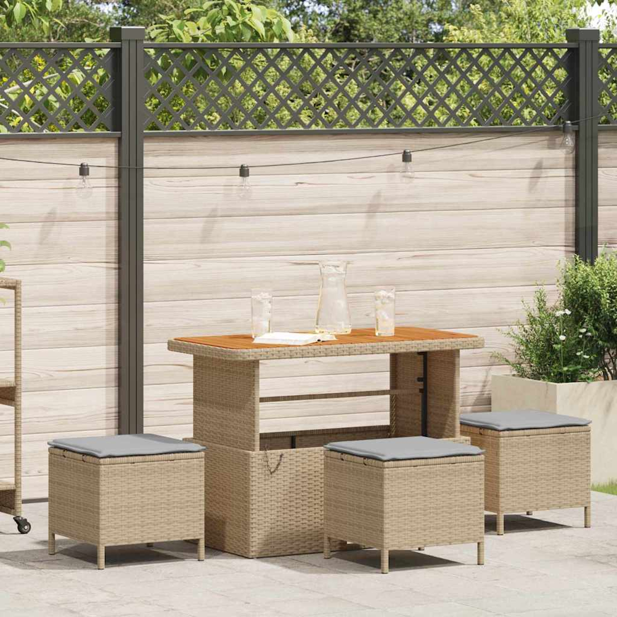 Szene im Freien mit Tisch, Hockern und Zaun. Der Tisch hat eine Holzplatte. Hocker sind würfelförmig mit grauen Kissen. Klare Gläser und ein Krug.