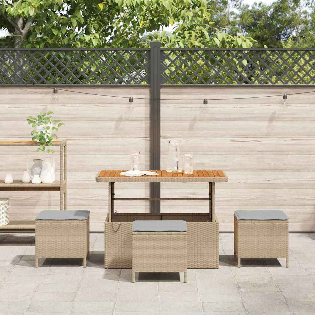Terrassenset mit Tisch, Hockern und Zierzaun. Der Tisch hat eine Holzplatte, die Hocker graue Kissen.