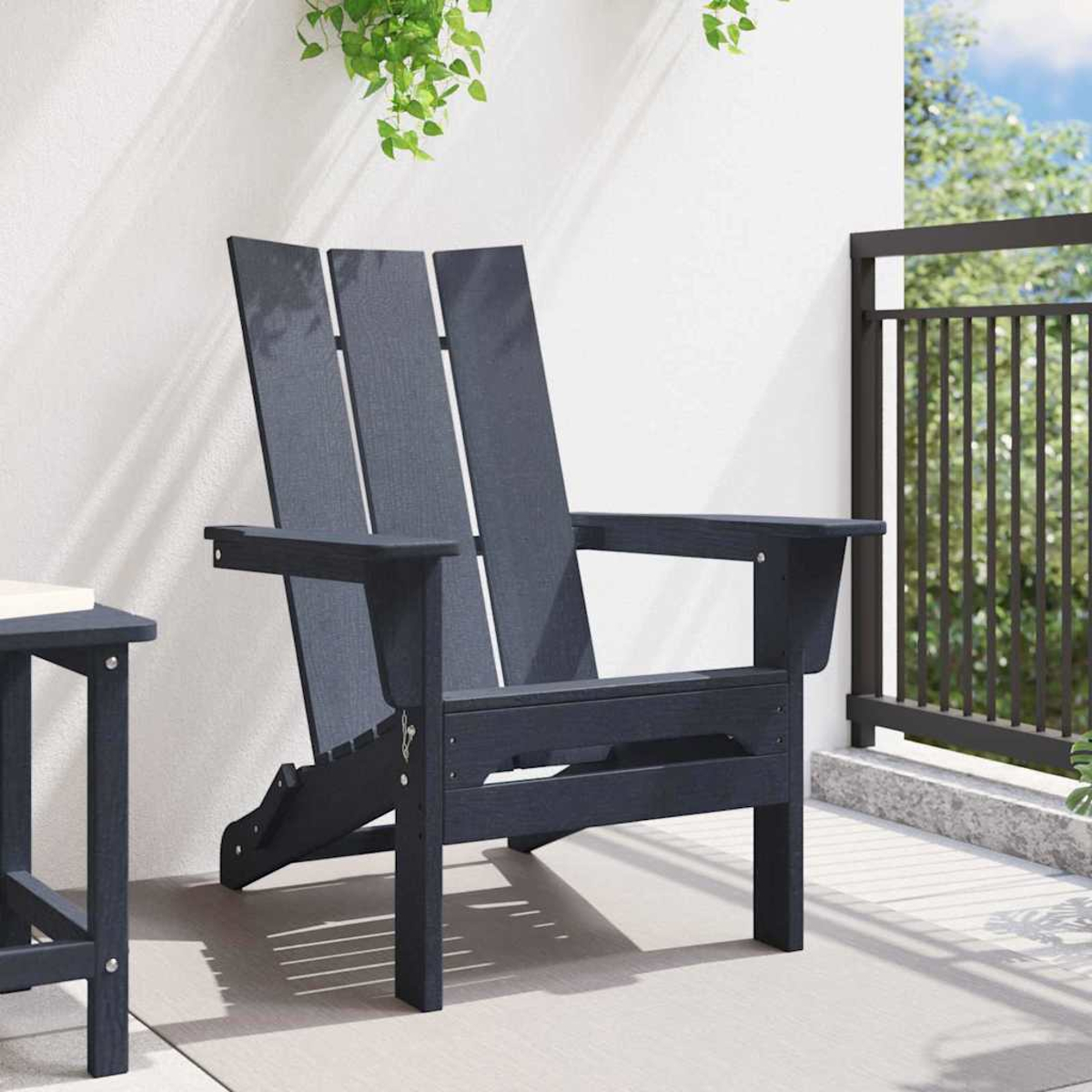 Una silla Adirondack azul oscuro en un patio. Plantas verdes cuelgan de arriba. Una mesa pequeña está a la izquierda. Una barandilla está a la derecha.