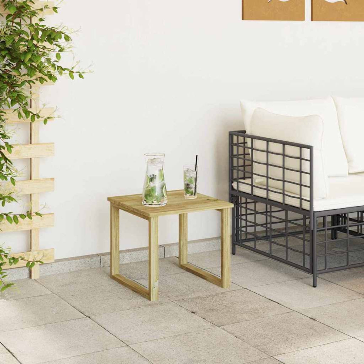 Holztisch mit Getränken, ein Metallsofa und eine Kletterpflanze vor einer weißen Wand auf einer Steinterrasse.