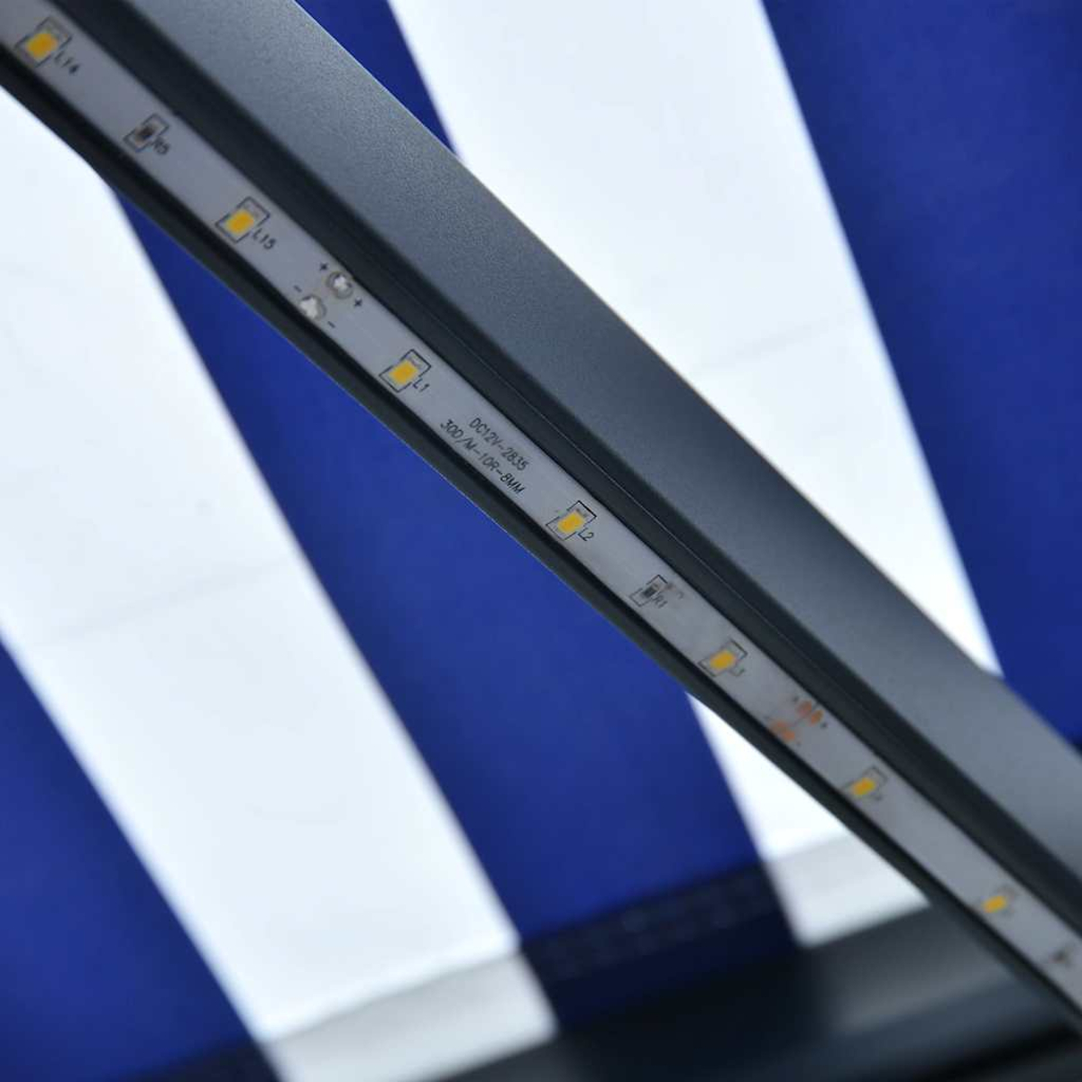 Nahaufnahme eines LED-Streifens auf einem grauen Rahmen. Hintergrund zeigt weiße und blaue Streifen. Der Streifen hat gelbe Lichter.