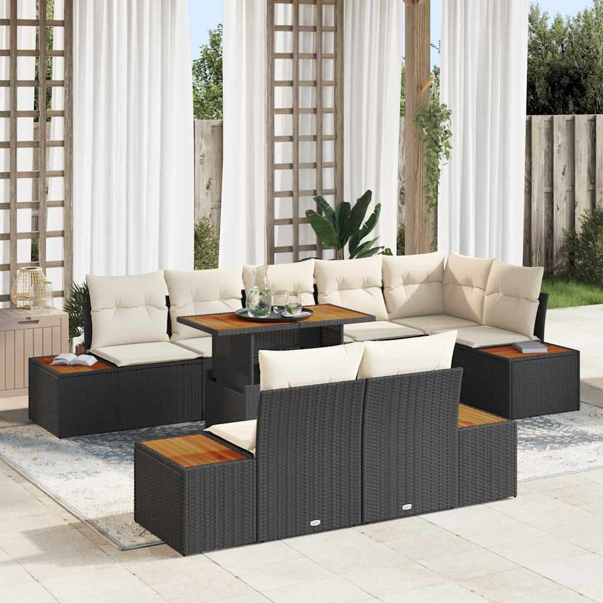 Juego de muebles de patio al aire libre con mimbre negro, tapas de madera y cojines crema, dispuestos alrededor de una mesa. Cortinas blancas al fondo.