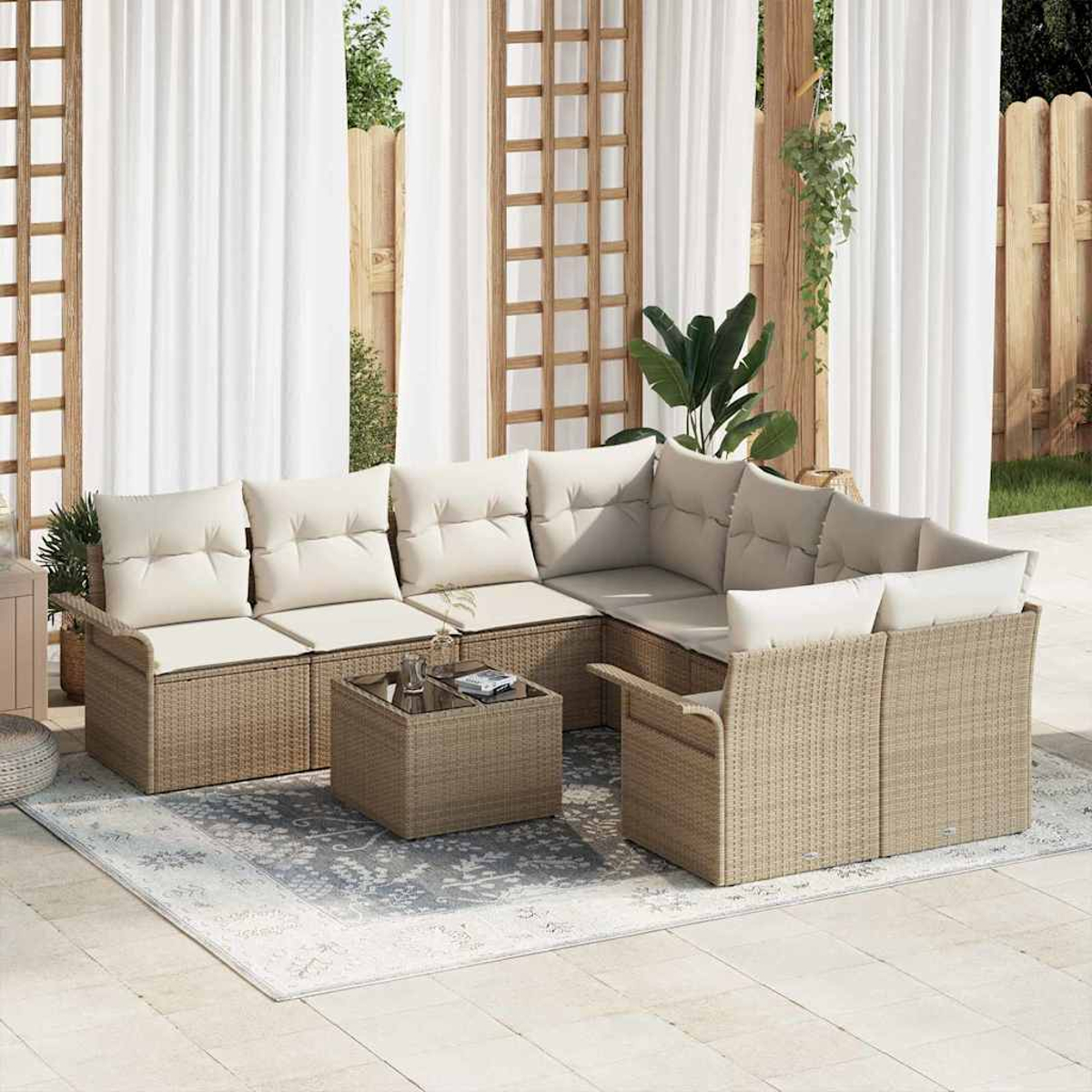 Ein Ecksofa aus Rattan mit cremefarbenen Kissen steht auf einem Teppich. Weiße Vorhänge und Holzgitter sind im Hintergrund.