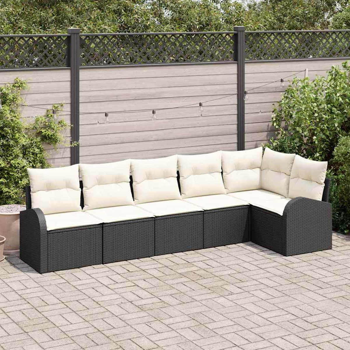 Ein Ecksofa im Freien mit cremefarbenen Kissen steht auf einer Ziegelpflasterung. Im Hintergrund ein Holzzaun und Grün.