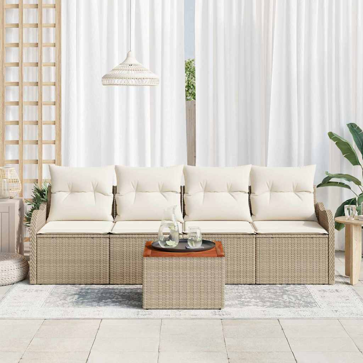Ein Korbmöbel-Sofa mit cremefarbenen Kissen, ein passender Couchtisch und weiße Vorhänge bilden einen Sitzbereich im Freien.