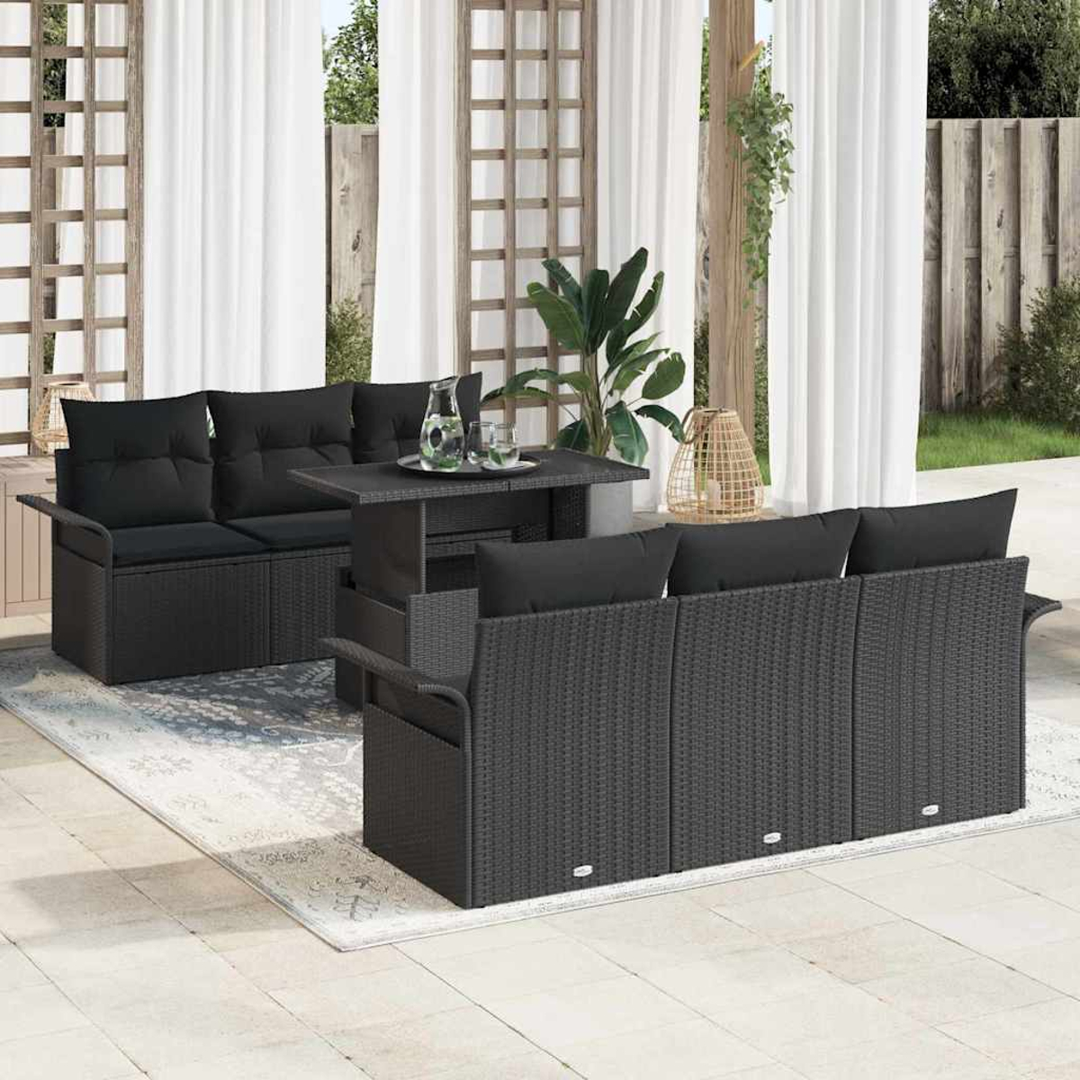 Terrassenset mit schwarzen Korbmöbeln, Kissen und einem Tisch. Inklusive Teppich, Pflanzen und Vorhängen.