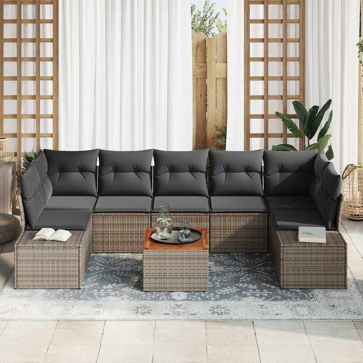 Outdoor-Ecksofa mit grauen Kissen und einem kleinen Tisch vor einem Fenster mit weißen Vorhängen. Ein Teppich befindet sich im Vordergrund.