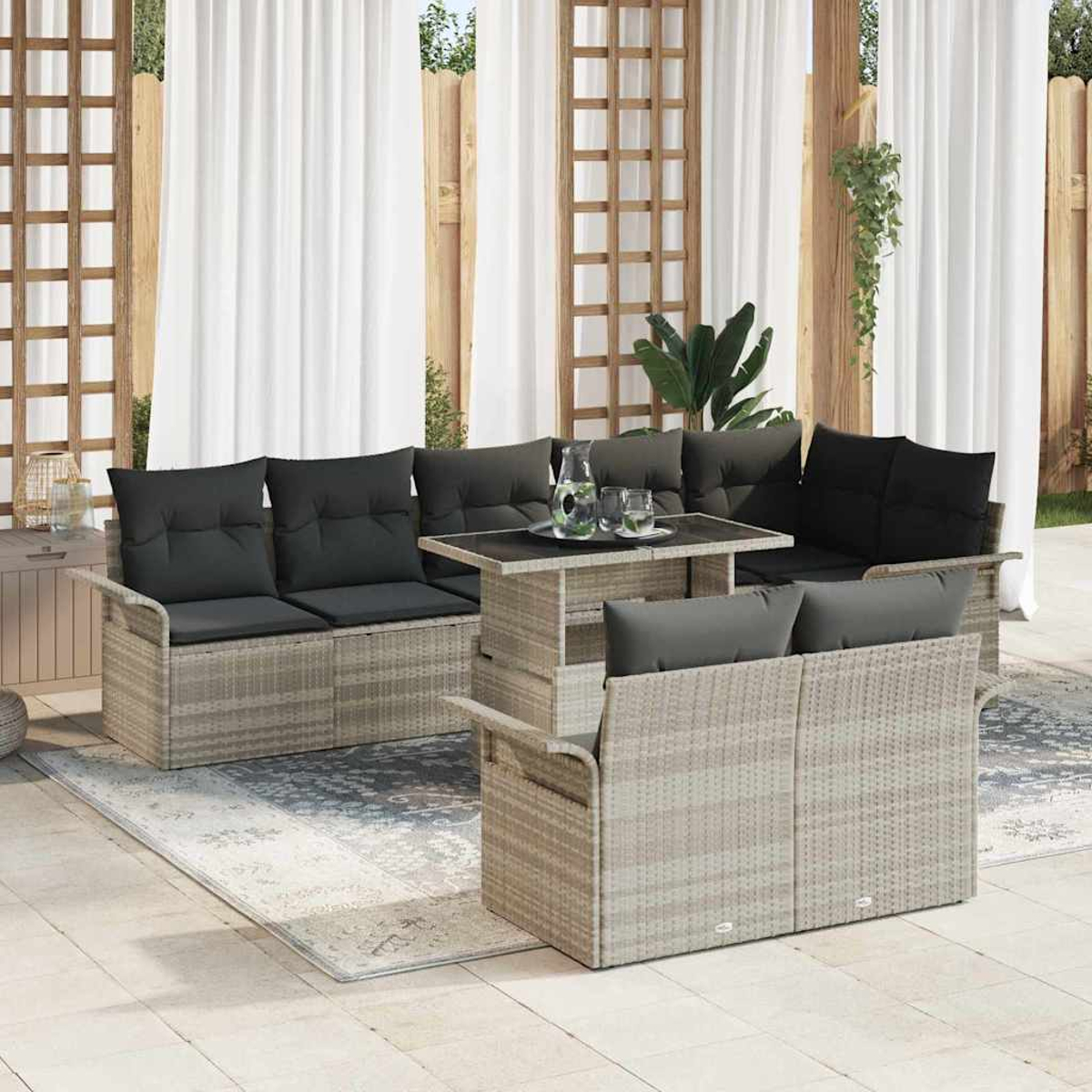 Terrassenset mit hellgrauen Korbmöbeln, schwarzen Kissen und einem Tisch mit Glasplatte. Weiße Vorhänge und Holzgitter im Hintergrund.