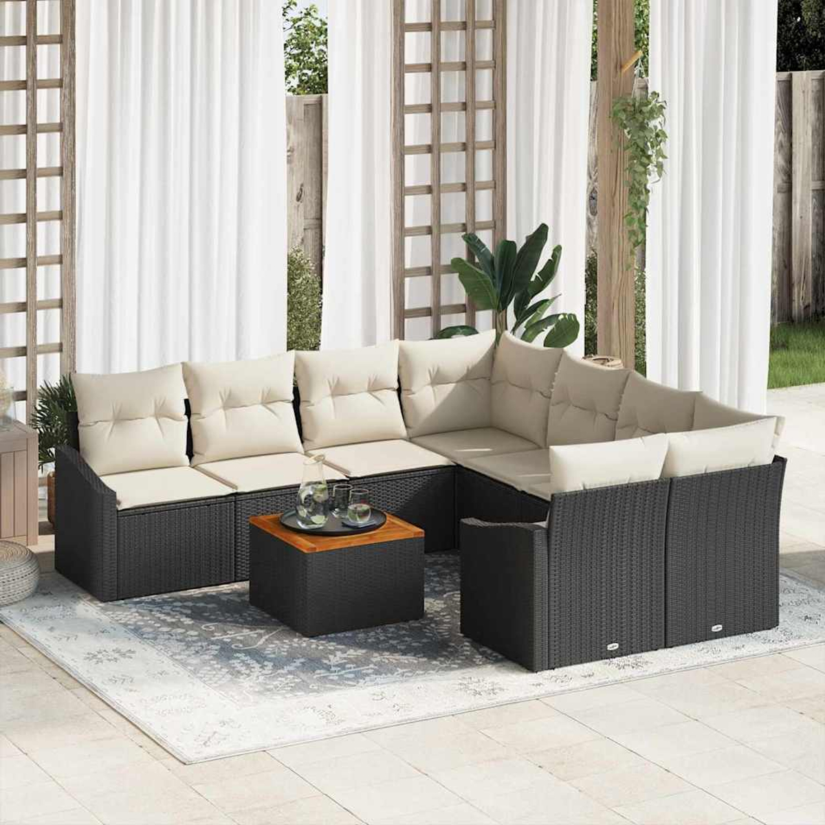 Sofá seccional para exteriores con cojines beige y una mesa de centro de madera. Cortinas blancas y una alfombra en el patio están en el fondo.