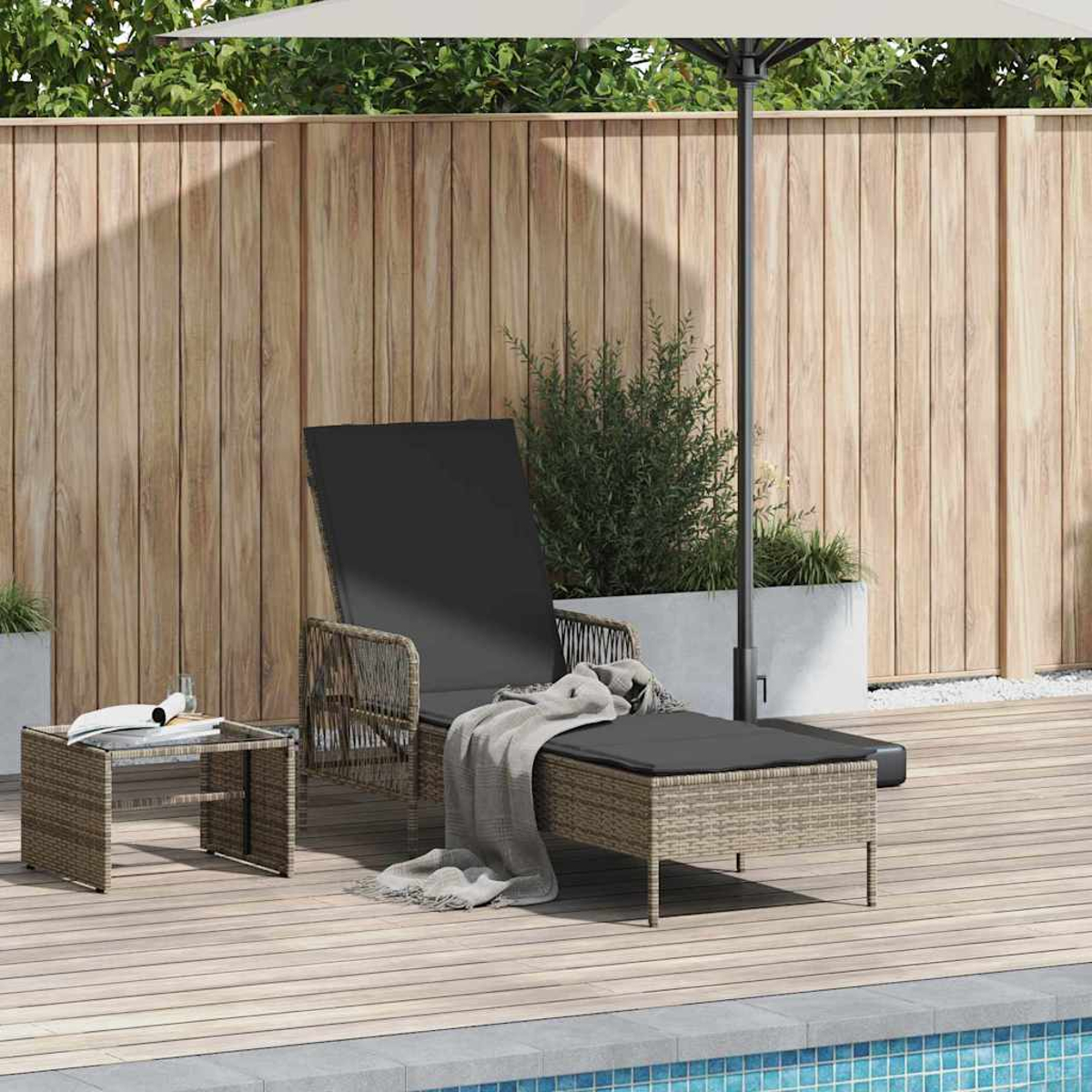 Eine Terrasse mit Liegestuhl, Beistelltisch und Sonnenschirm in der Nähe eines Pools. Eine Decke liegt auf dem Stuhl. Holzzaun im Hintergrund.
