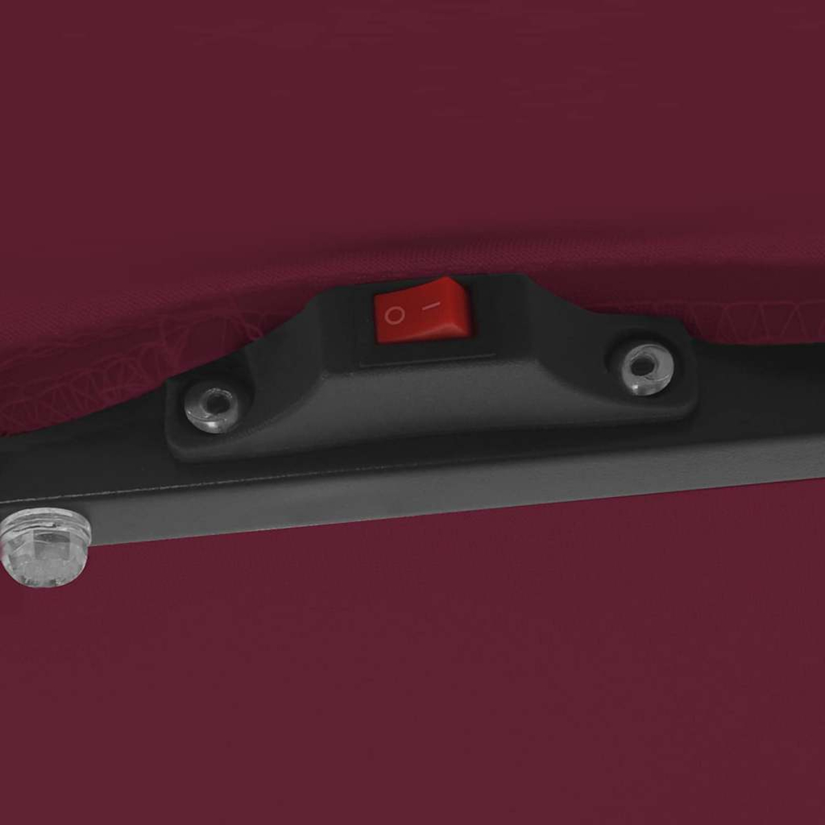 Primo piano di una superficie bordeaux con una cornice nera. Un interruttore rosso è al centro. Sono visibili anche viti e una manopola trasparente.