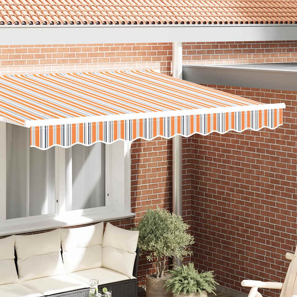 Ein orange-weiß gestreiftes Sonnensegel über einem Fenster, eine rote Backsteinmauer und ein Sofa mit weißen Kissen.