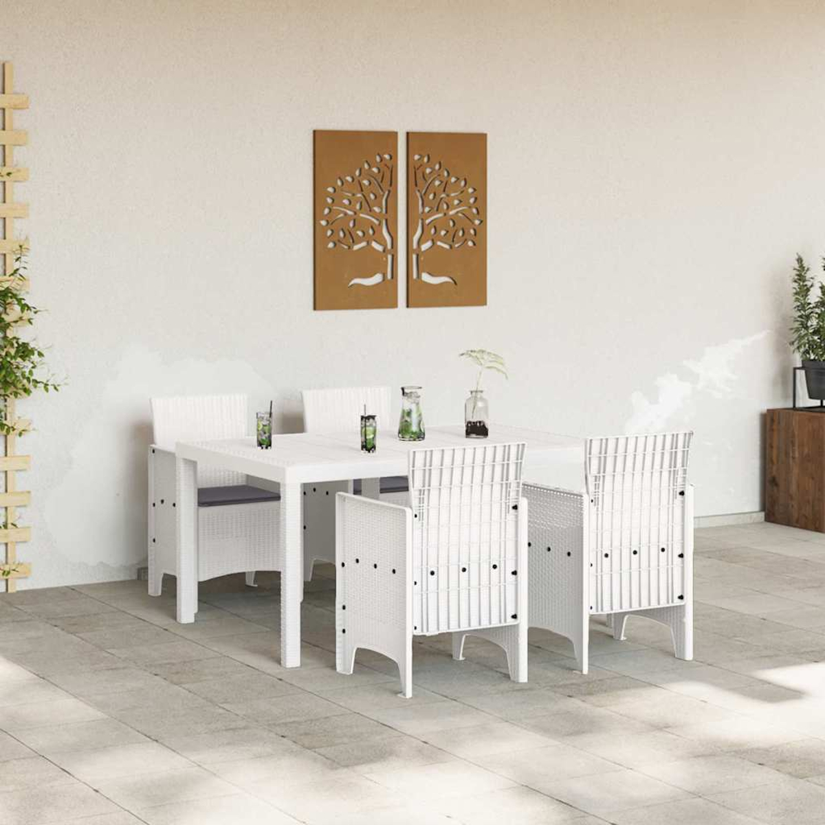 Weißes Terrassenset mit Tisch und Stühlen. Zwei Baumkunstwerke an der Wand. Getränke auf dem Tisch. Pflanzen sind sichtbar.