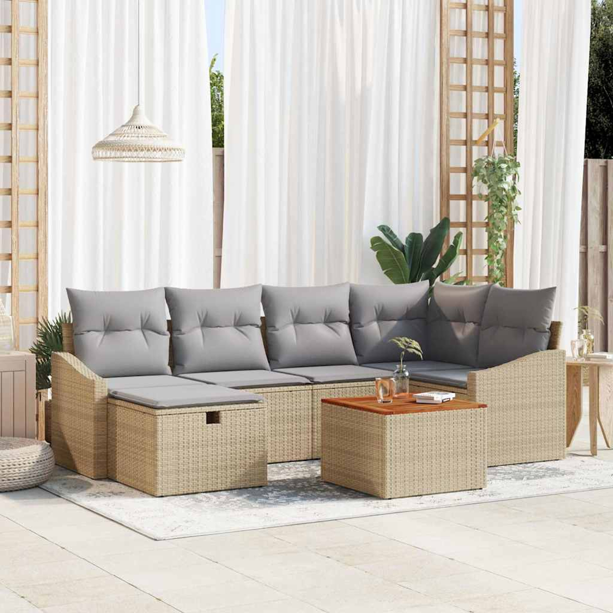 Outdoor-Wicker-Möbelset mit grauen Kissen, einem Couchtisch und weißen Vorhängen im Hintergrund. Über dem Set hängt eine Pendelleuchte.