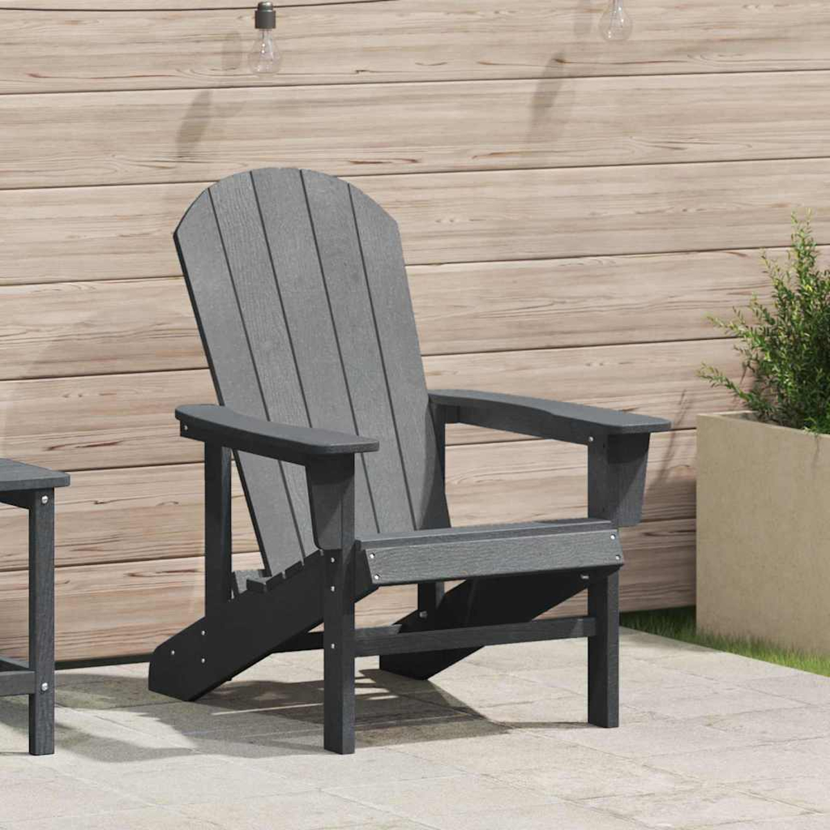 Ein grauer Adirondack-Stuhl steht auf einer Terrasse. Im Hintergrund Holzverkleidung und eine Pflanze. Leuchten sind sichtbar.