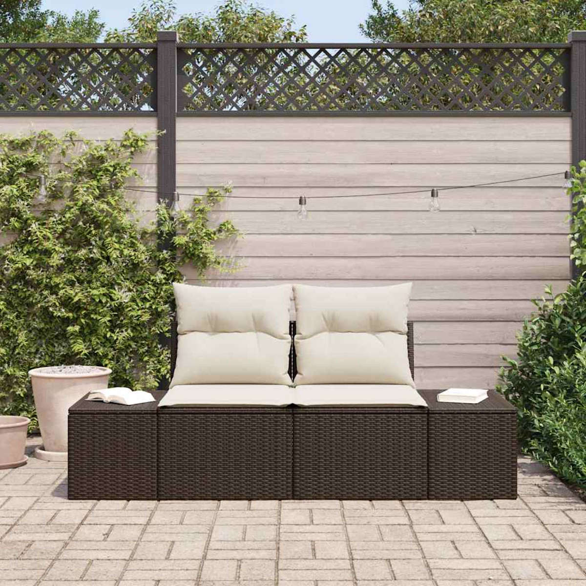 Asientos al aire libre con cojines beige. Estructura tejida marrón oscuro. Fondo: valla, plantas y patio pavimentado.