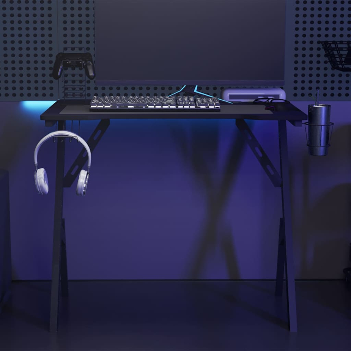 Gaming-Schreibtisch mit Tastatur, Monitor, Headset und Controller. Schwarz und Blau dominieren. Auf der Seite ist ein Becherhalter.