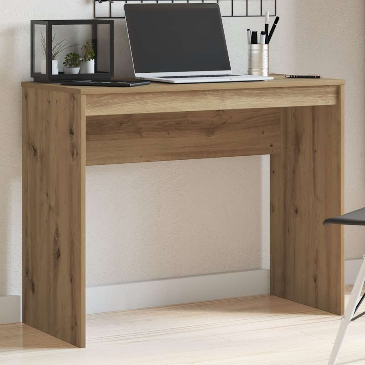 Ein Holztisch mit Laptop, Stiften und einer Pflanze. Ein schwarzes quadratisches Regal steht auf dem Tisch. Rechts ein schwarzer Stuhl.