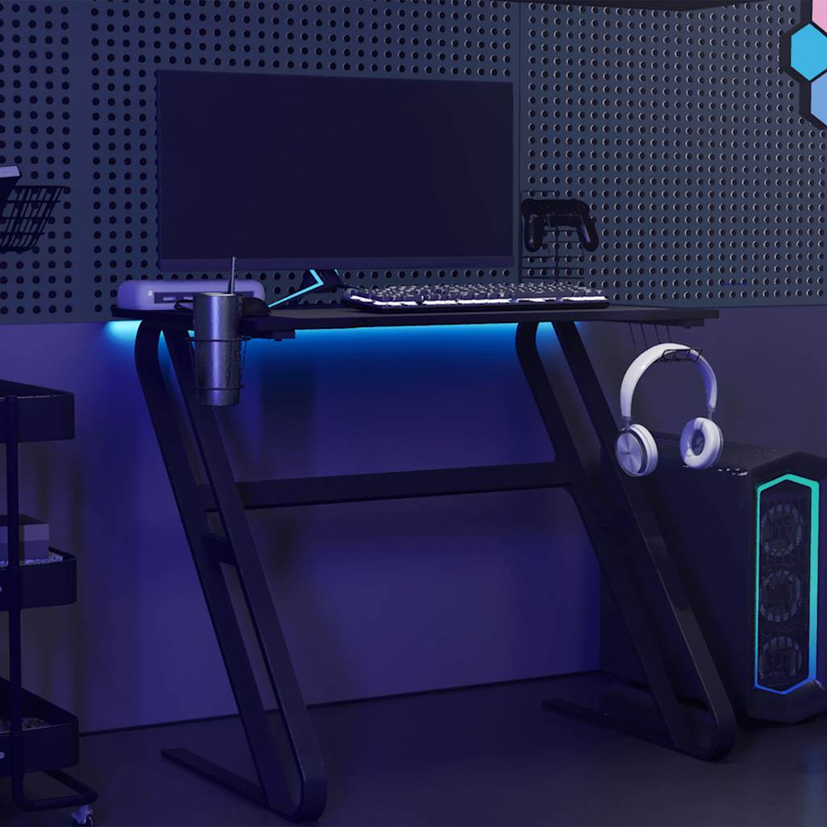 Gaming-Setup mit Monitor, Tastatur, Kopfhörern und Computer. Der Schreibtisch hat blaue LED-Beleuchtung. Die Wand ist dunkel mit kleinen Löchern.