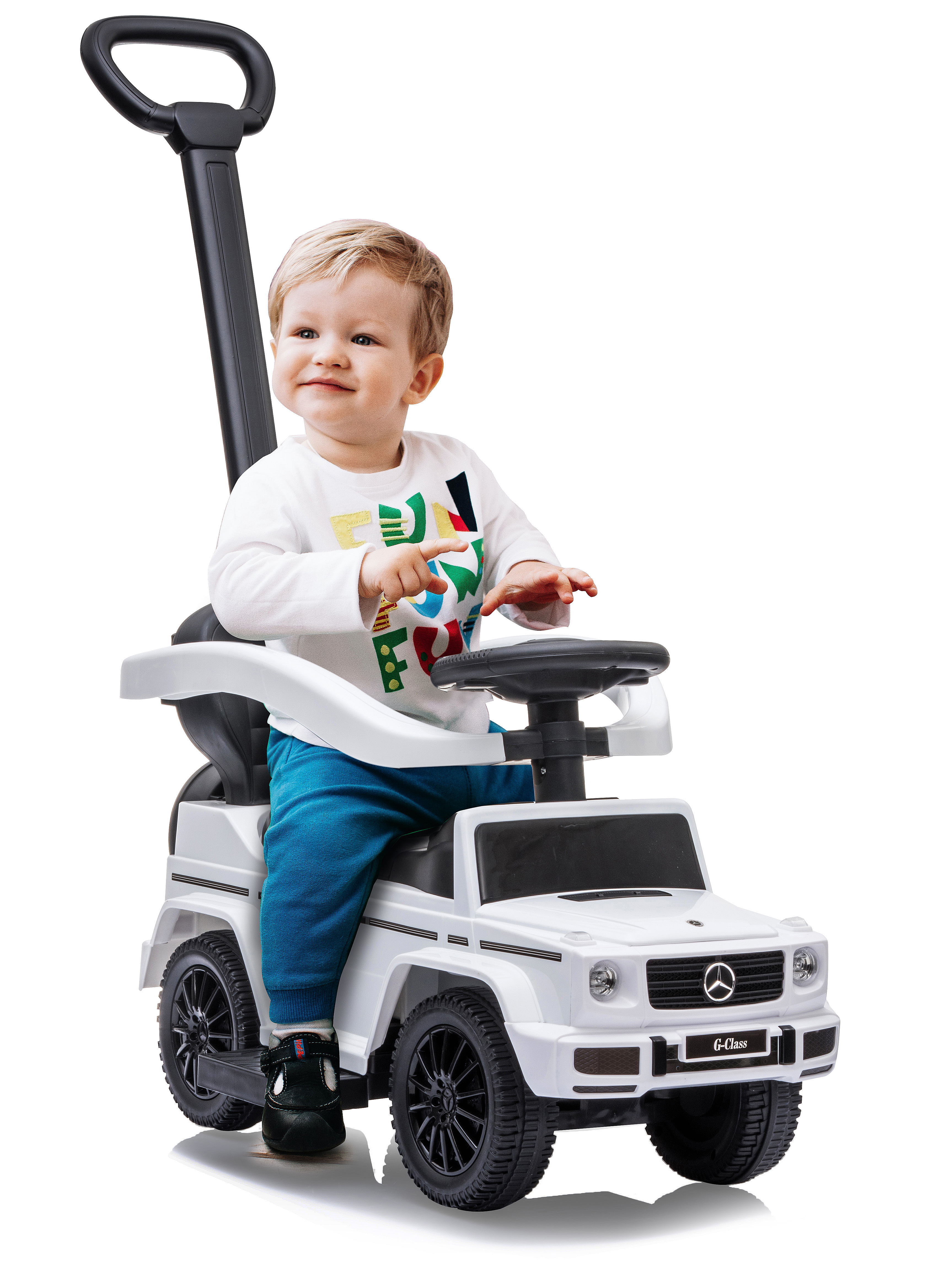 Un bambino è seduto in un'auto giocattolo bianca con un volante. Il bambino indossa pantaloni blu e una camicia bianca. C'è una maniglia nera in alto.