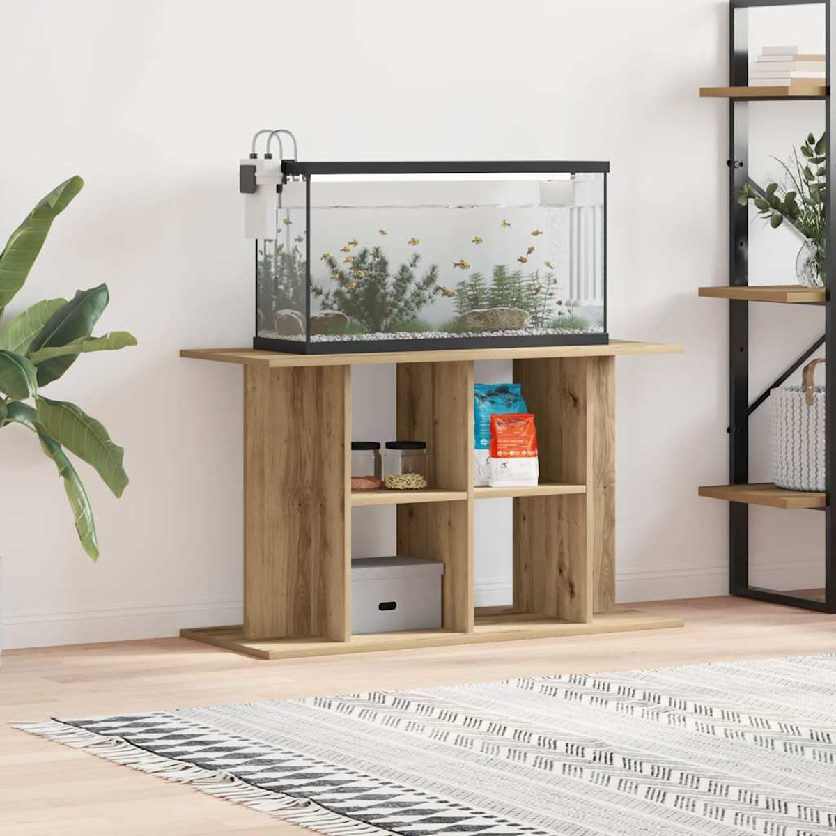 Ein Aquarium auf einem Holzständer. Fische schwimmen darin. Regale darunter halten Gläser, eine Box und Tiernahrung. Eine Pflanze und ein Teppich sind im Vordergrund.