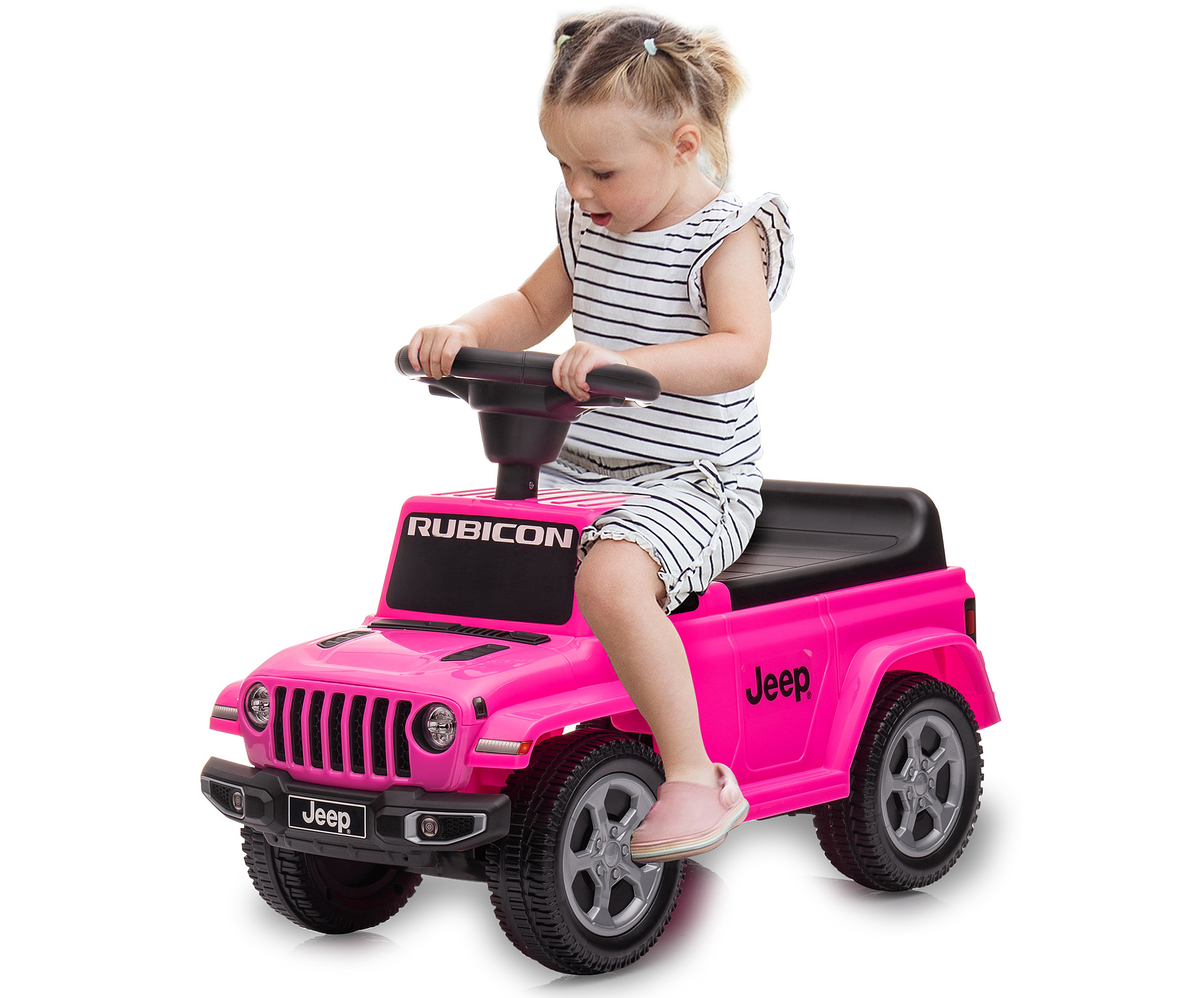Ein Mädchen in gestreifter Kleidung sitzt in einem rosa Spielzeug-Jeep. Sie hält das Lenkrad. Das Auto sagt 'Rubicon'.