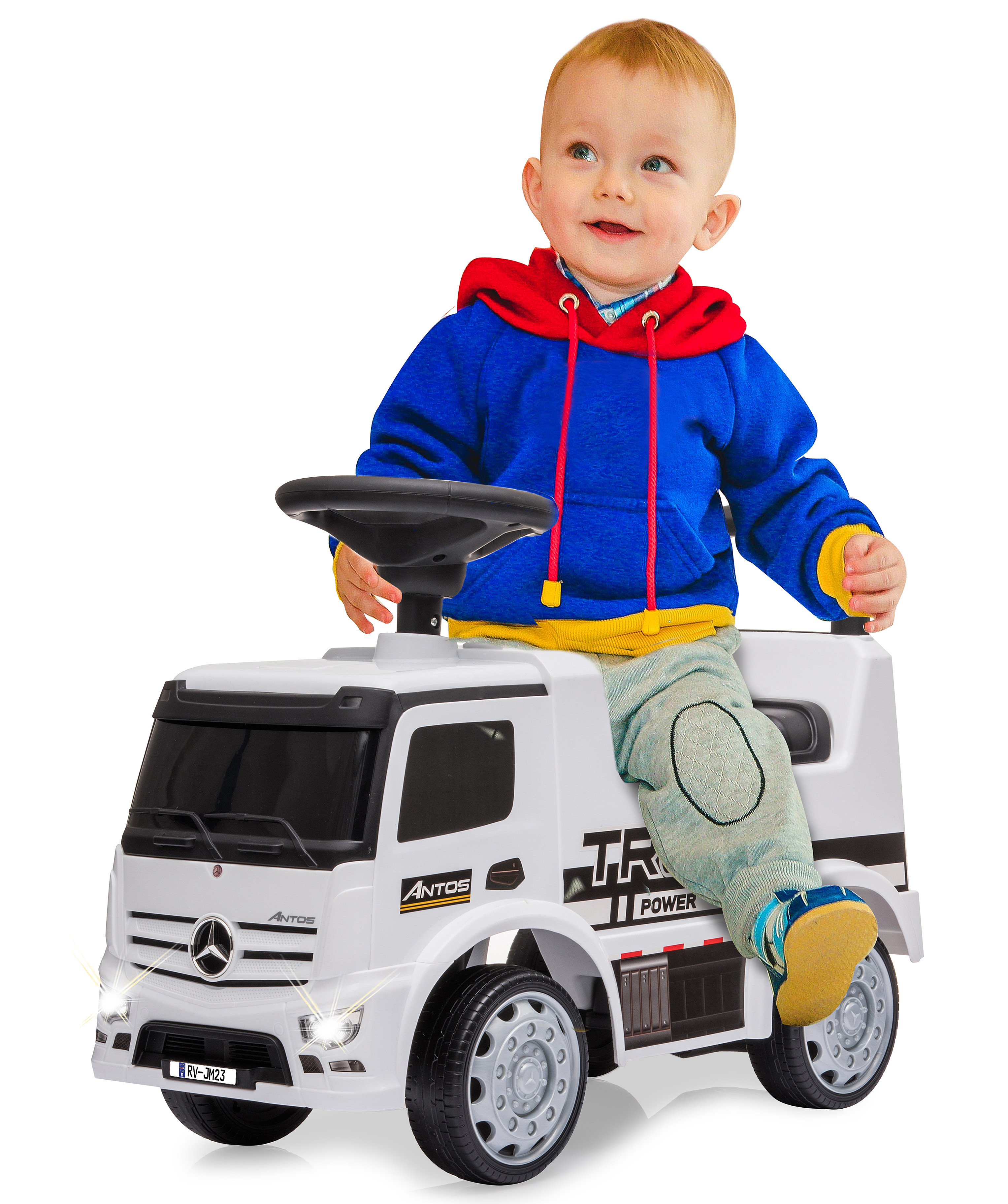 Uśmiechnięte dziecko siedzi na białej zabawce ciężarówce z niebieską i czerwoną bluzą z kapturem. Ciężarówka ma czarne koła i światła.