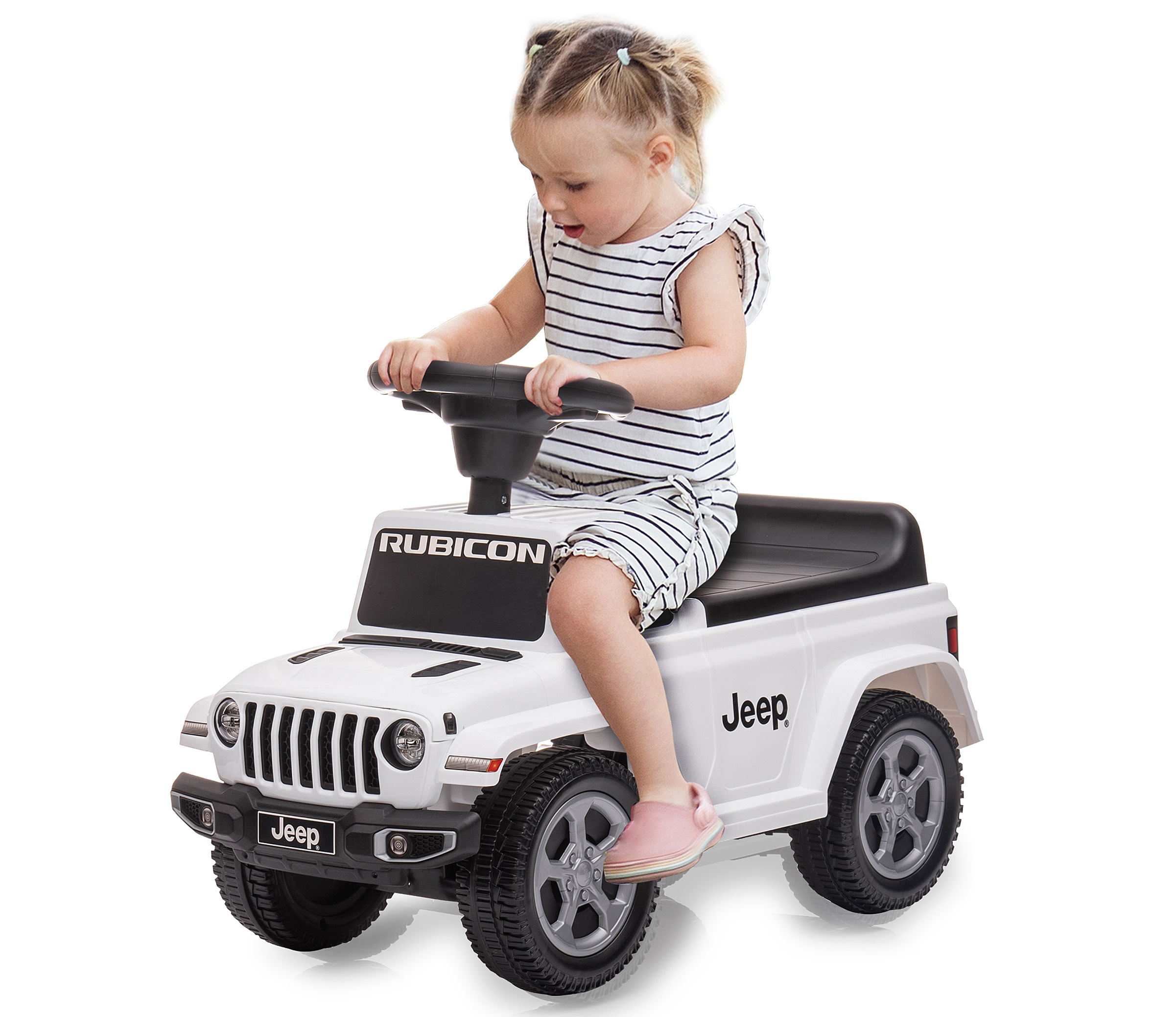Ein junges Mädchen in einem gestreiften Kleid sitzt auf einem weißen Jeep-Spielzeugauto und hält das Lenkrad.