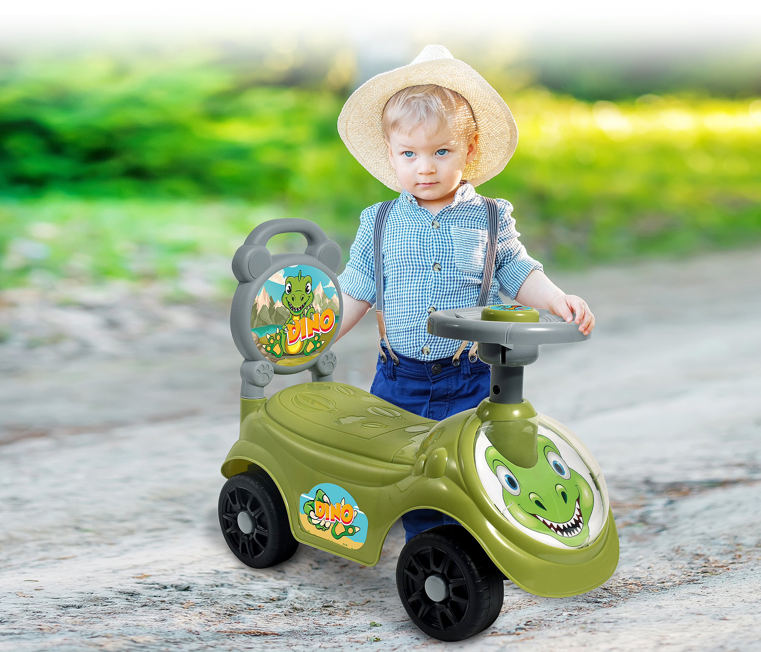 Ein kleiner Junge mit Strohhut und Hosenträgern steht neben einem grünen Spielzeugauto mit Dinosaurier-Design.