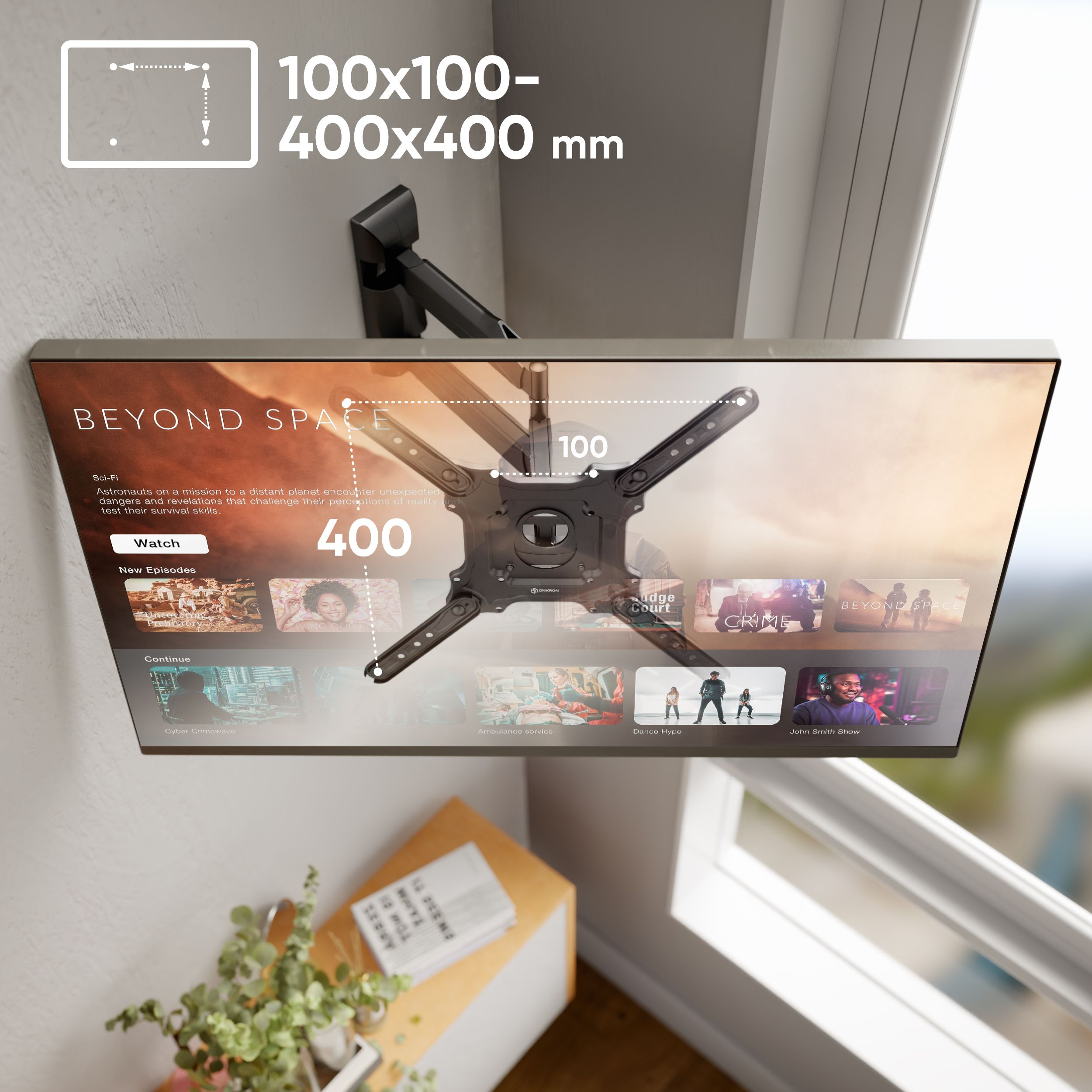 Telewizor na uchwycie ściennym. Telewizor wyświetla treści strumieniowe. Mały stolik z rośliną i książkami na dole.