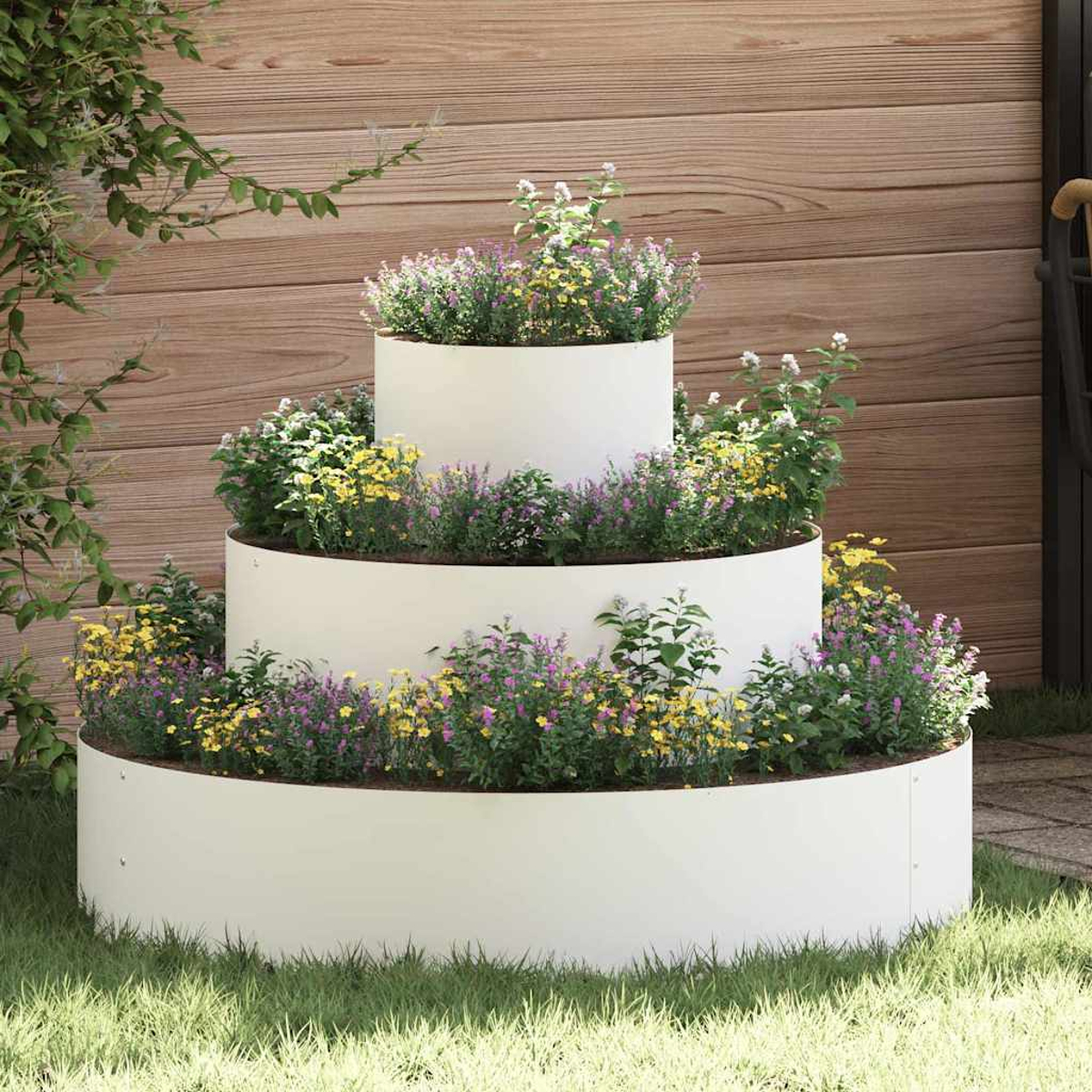 Una fioriera bianca a più livelli con fiori colorati. Recinto di legno sullo sfondo, erba verde in primo piano e rampicanti laterali.