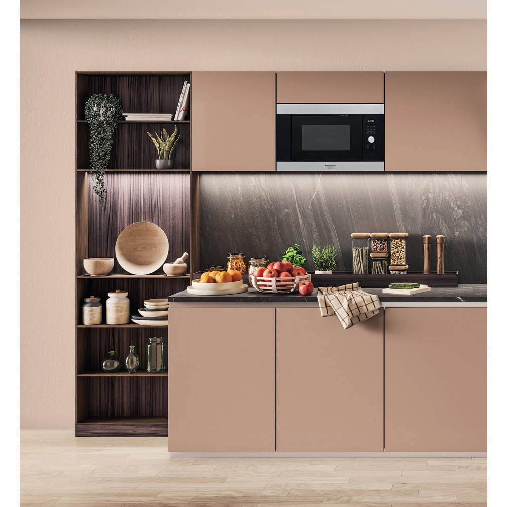 Cocina moderna con microondas empotrado, estantes, frutas y varios utensilios de cocina. La combinación de colores es beige y marrón.