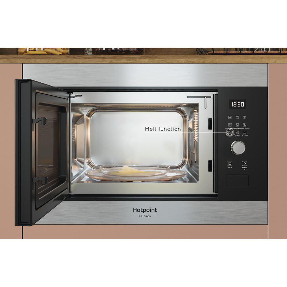 Microondas abierto con plato de cristal. Panel de control negro con botones y pantalla. Marca Hotpoint Ariston.