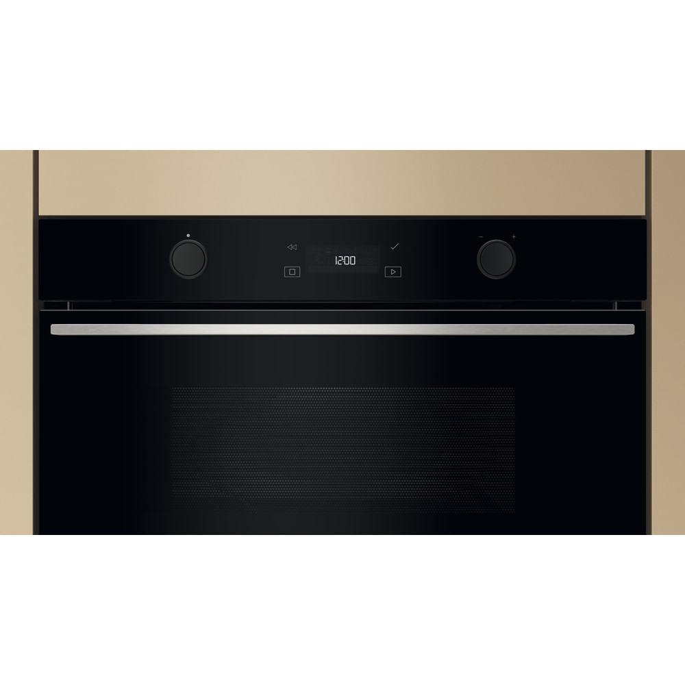 Un forno nero con orologio digitale che mostra le 12:00. Ha manopole e maniglia in acciaio inox. Cornice del mobile beige.