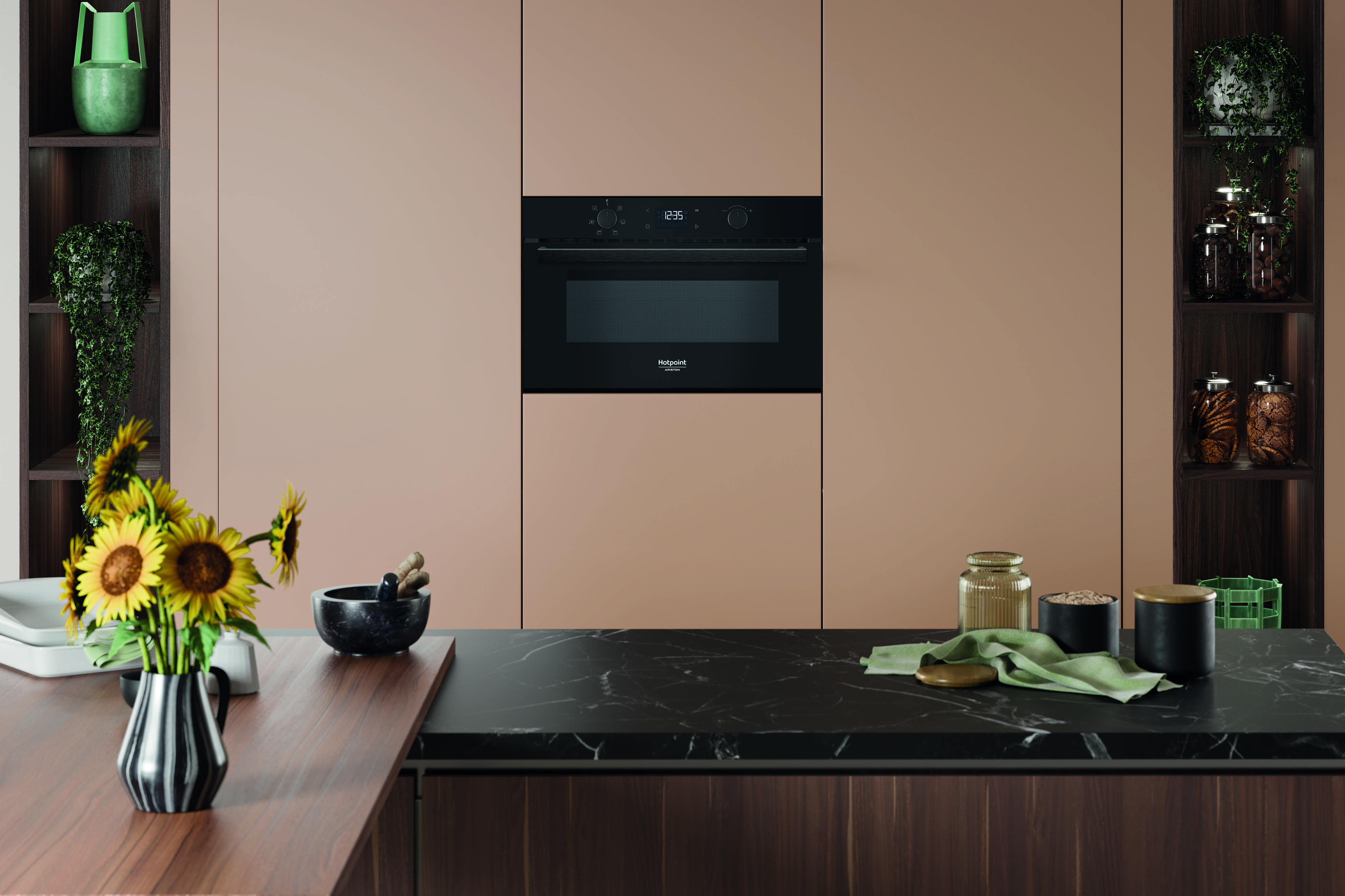 Scena cucina con microonde incassato, mobili in legno, girasoli ed elementi decorativi su un piano di lavoro.