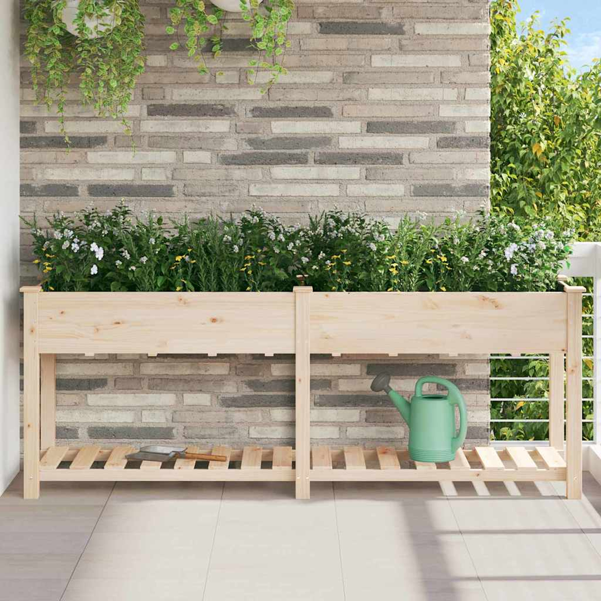 Fioriera in legno con piante su un balcone. Un annaffiatoio e una cazzuola sono all'interno. Un muro di mattoni sullo sfondo.