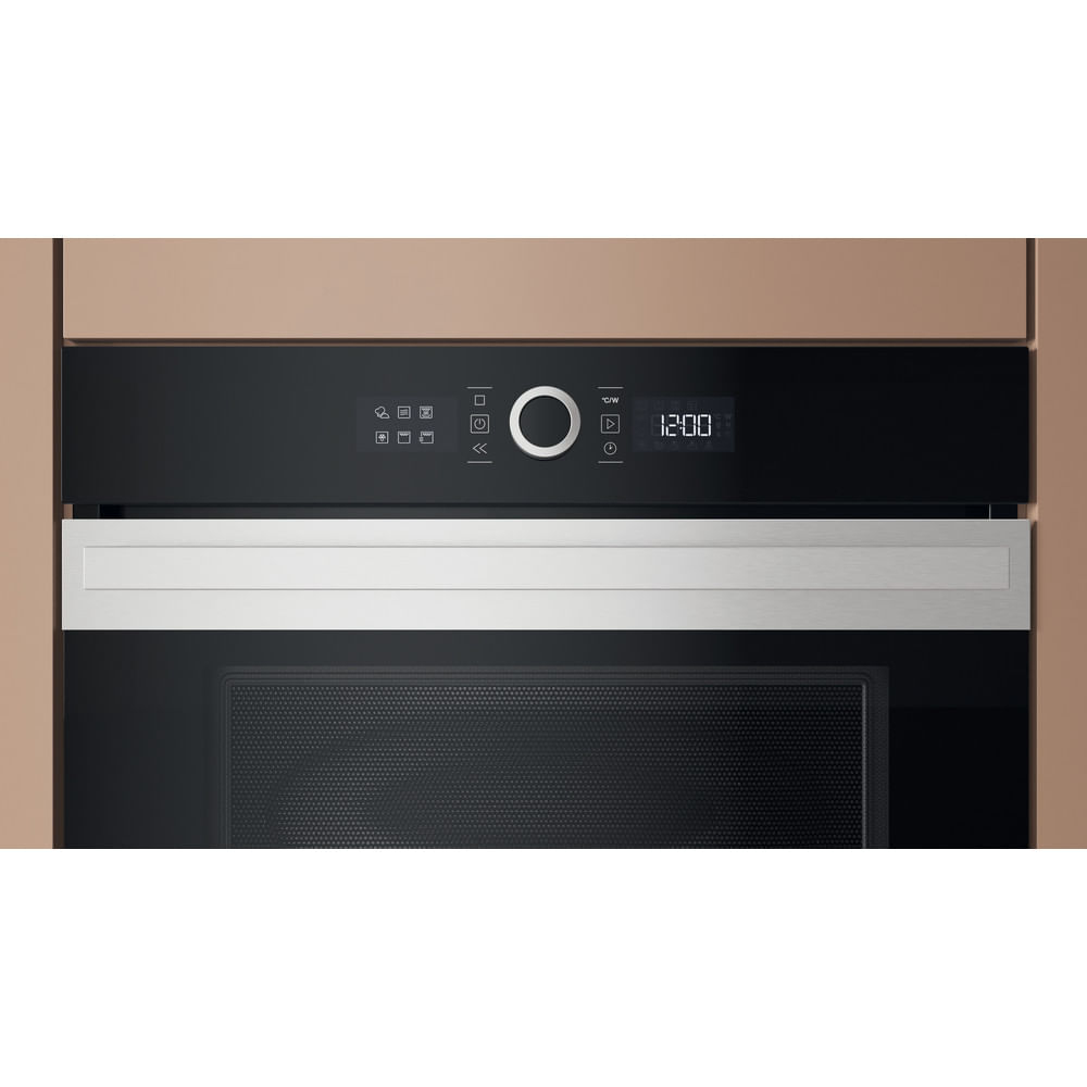 Primo piano di un forno nero con display digitale che mostra le 12:00. Ha finiture e pulsanti argentati. Lo circonda un mobile beige.
