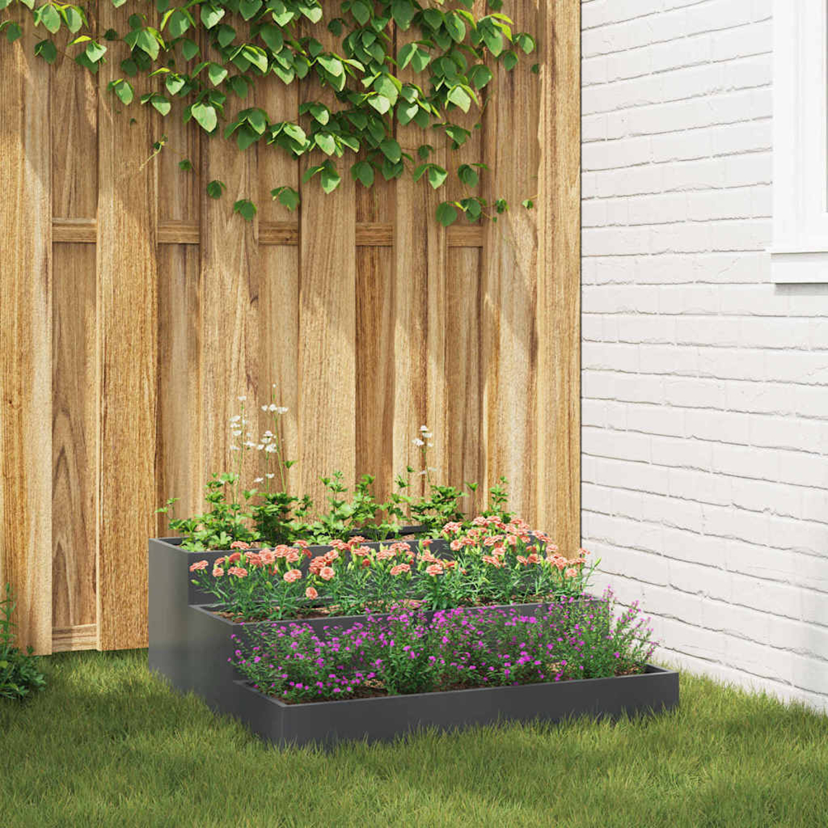 Una fioriera a più livelli piena di fiori rosa e viola è posizionata sull'erba. Una staccionata in legno e un muro di mattoni bianchi formano lo sfondo.
