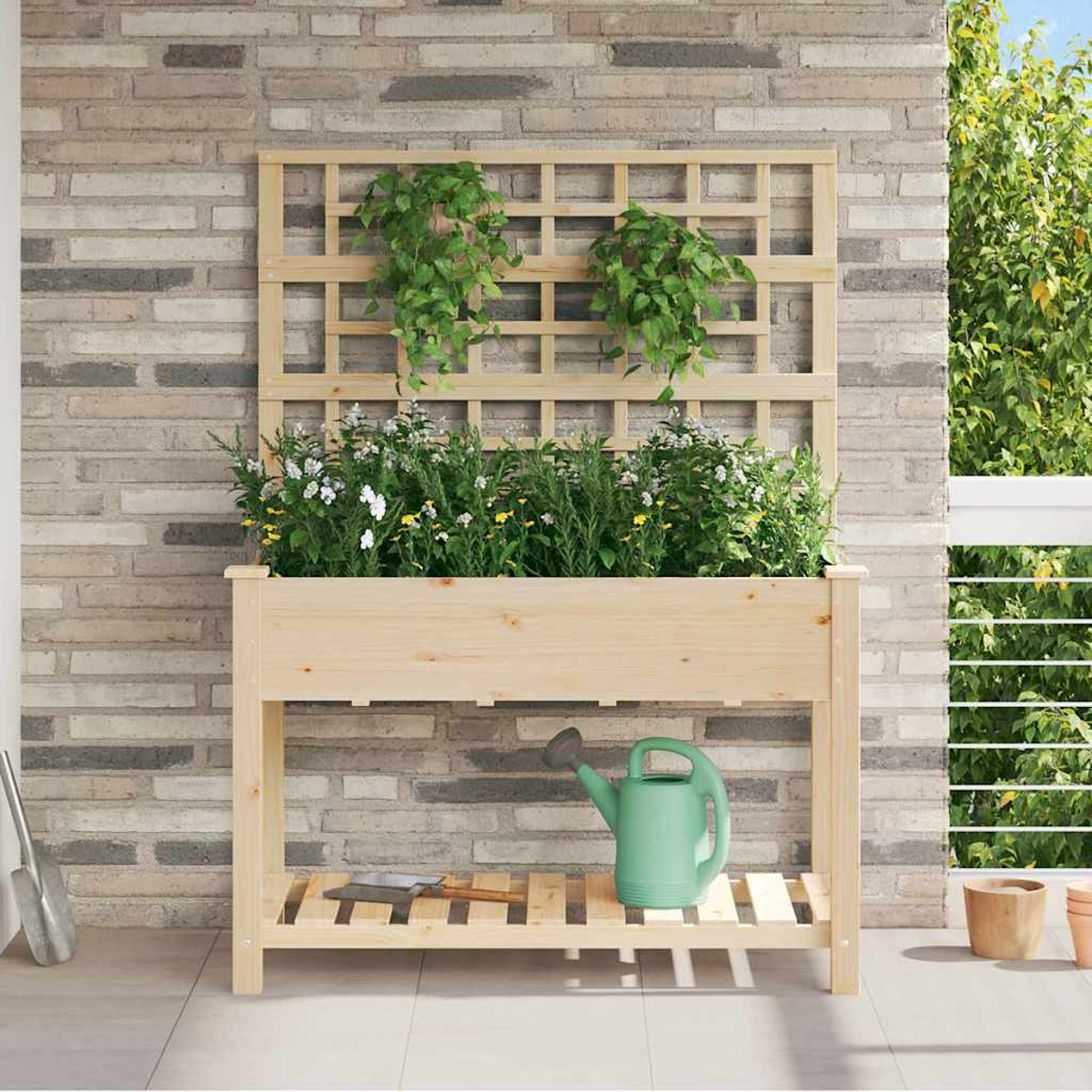 Fioriera in legno con piante contro un muro di mattoni. Un annaffiatoio e attrezzi da giardinaggio sono sullo scaffale sottostante. Fogliame verde.