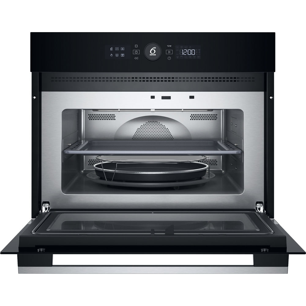 Forno a microonde aperto con porta a vetri. All'interno un vassoio, una griglia rotonda in metallo e un piatto nero. Display digitale in alto.